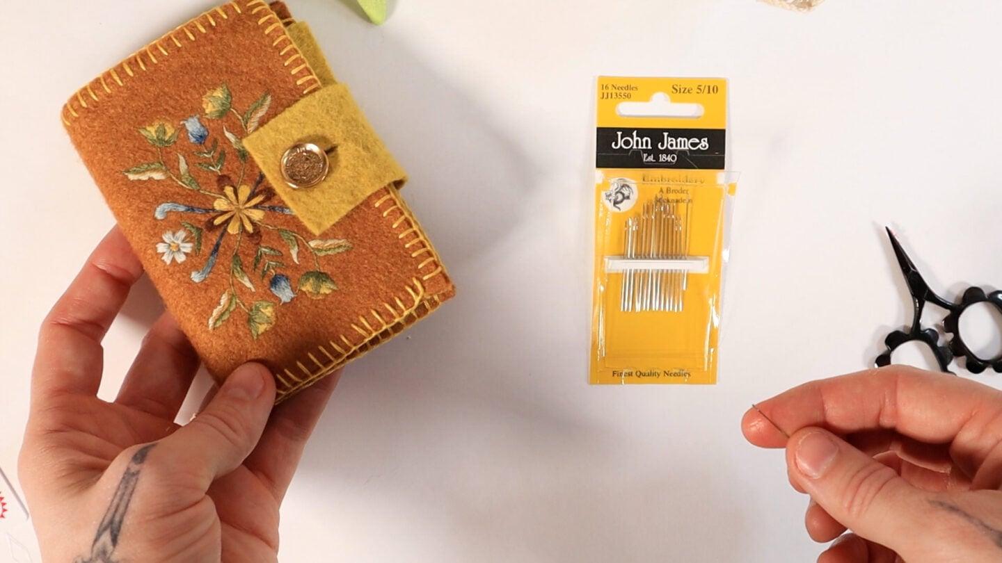 a pack of needles and a felt needle book that stores and organizes the needles