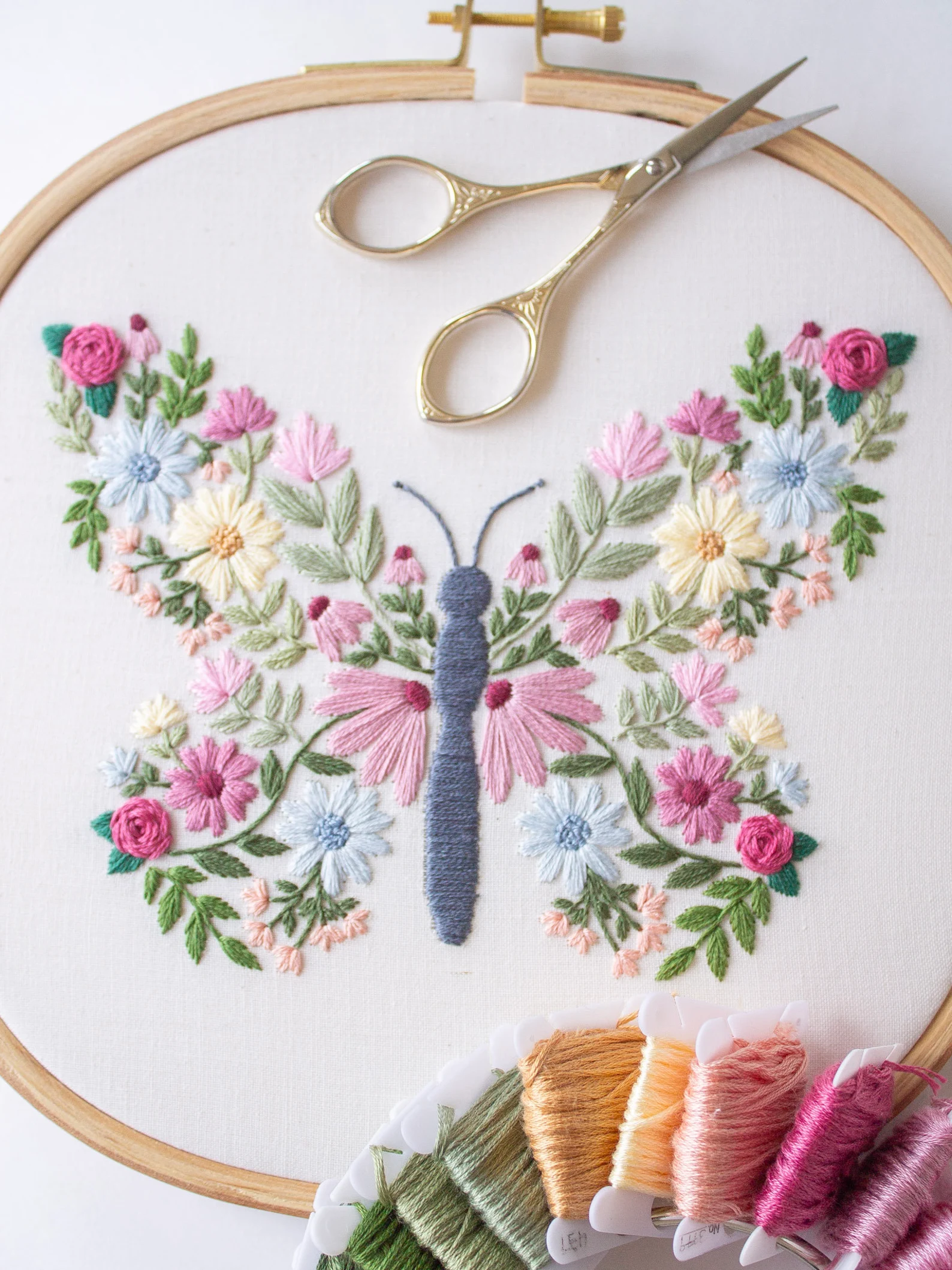 embroidery art in a butterfly shape made up of pastel flowers - artwork by ByAlyPloof