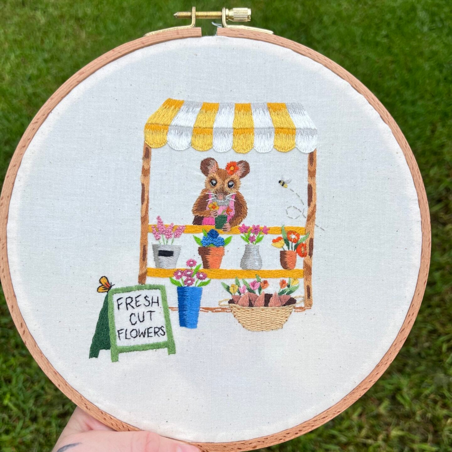 embroidery design of a mouse selling flowers at a flower stand