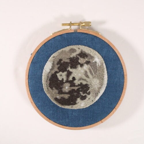 embroidery of a realistic full moon on dark blue fabric