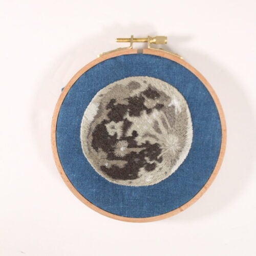 embroidery of a realistic full moon on dark blue fabric
