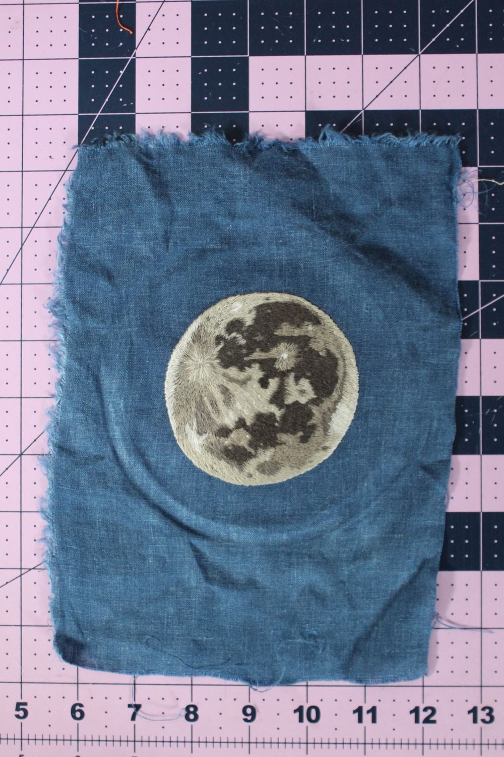 embroidery of a moon on dark blue fabric with hoop burn on the fabric