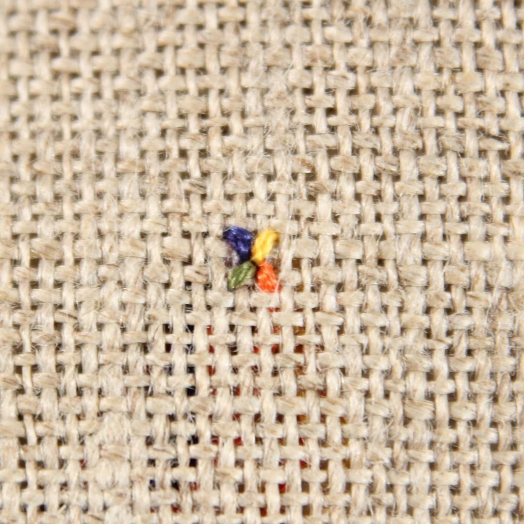 4 colorful quarter cross stitches stitched on beige linen
