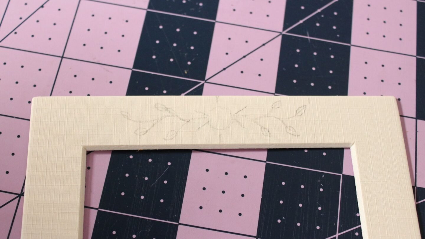 tracing the floral design onto the photo mat with pencil