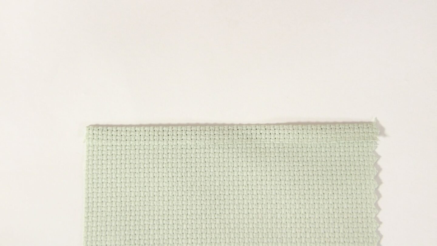 light green Aida fabric with a 1/4 inch edge folded over and pressed