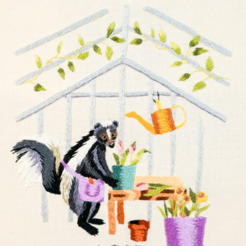 closeup of an embroidery of a skunk gardening in a greenhouse