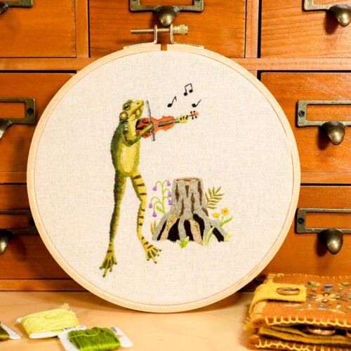embroidery of a frog playing a fiddle