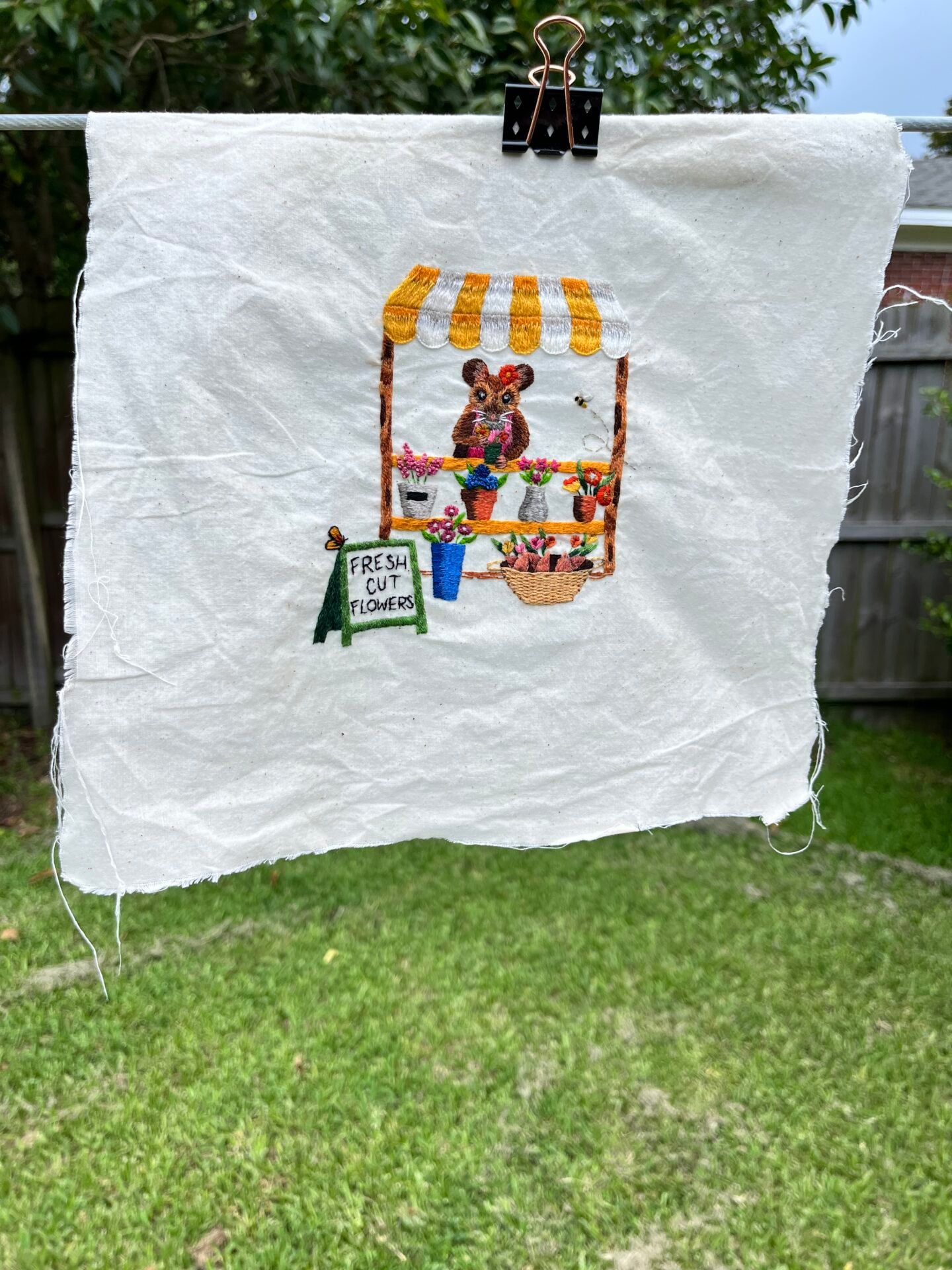 an embroidery of a mouse that was just washed to remove color bleeding, hang-drying on a clothesline