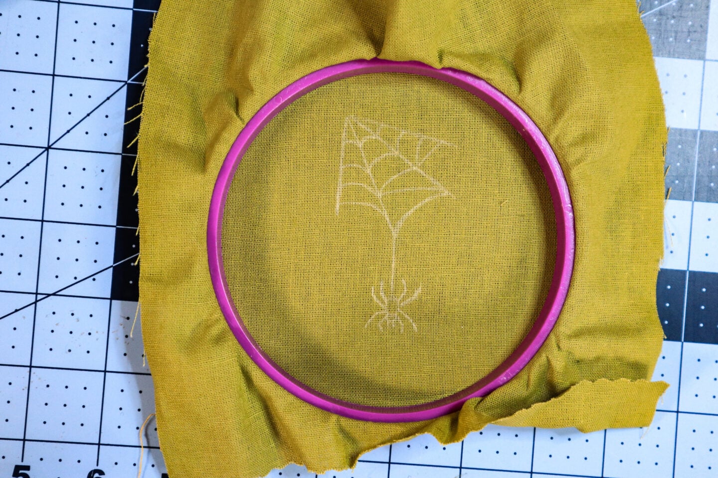 Spider and spiderweb design transferred to green fabric using white transfer pencil