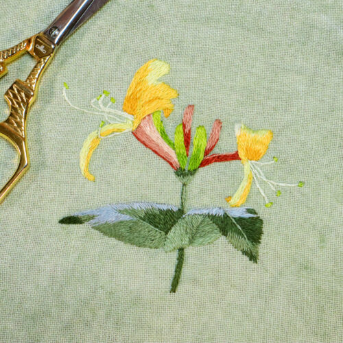 embroidery of yellow honeysuckles on green linen fabric
